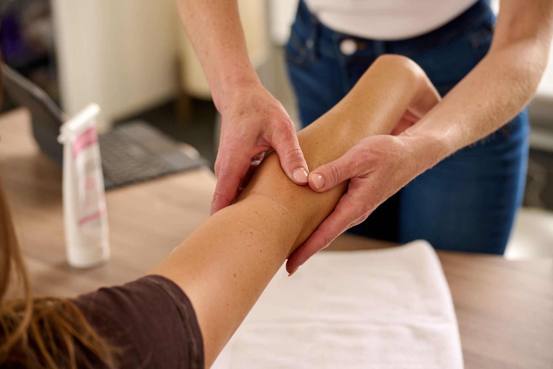 Kate's hands working on a patient's forearm during a hand therapy session